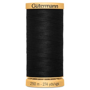 May include: A spool of black sewing thread with a tan plastic top and bottom. The top label reads G&uuml;termann in black text. The bottom label displays the length as 250 m - 274 yds/vgs. The thread is wound in a cross-hatch pattern around the cylinder.