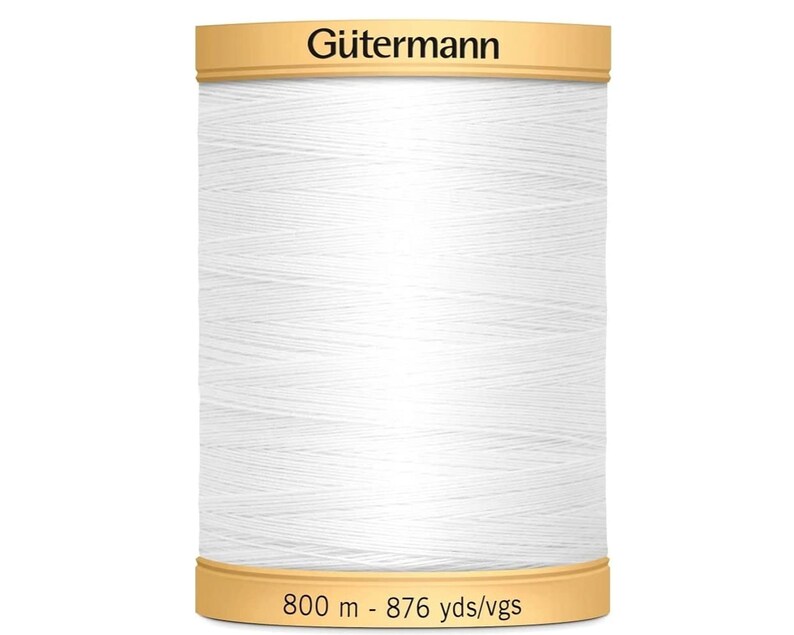 May include: A spool of white sewing thread by G&uuml;termann. The top label displays the brand name G&uuml;termann in black text. The bottom label indicates a length of 800 m - 876 yds/vgs. The thread is wound tightly around the cylindrical spool core.