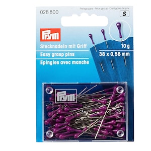 May include: A packet of sewing pins with purple heads. The packaging includes the text "Easy grasp pins" and measurements of 38 x 0.58 mm. The pins are in a clear plastic container with a blue background. The brand name "Frym" is also visible.