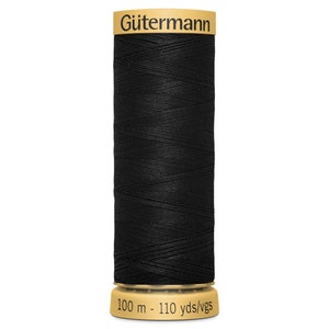 May include: A spool of black sewing thread by G&uuml;termann. The top label features the brand name in black text on a gold background. The bottom base is gold and displays the text 100 m - 110 yds/vgs, indicating the length of the thread on the spool.