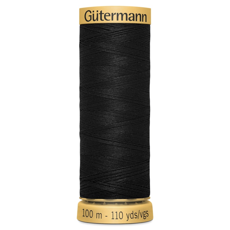 May include: A spool of black sewing thread by G&uuml;termann. The top label features the brand name in black text on a gold background. The bottom base is gold and displays the text 100 m - 110 yds/vgs, indicating the length of the thread on the spool.