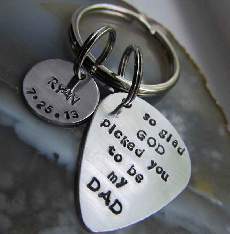 May include: Silver keychain with two charms. One charm is a round disc with the text "Ryan 7.25.13". The other charm is a guitar pick shape with the text "so glad GOD picked you to be my DAD".