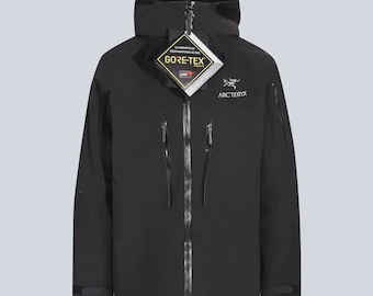 May include: A black hooded jacket featuring a central zipper, two vertical chest pockets with black zippers, and the Arc'teryx logo on the upper left chest. A Gore-Tex product tag hangs from the collar with text in French and English.