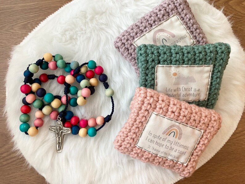 Peut inclure: Un chapelet en bois color&eacute; avec un crucifix en argent, trois pochettes en crochet avec des citations inspirantes et des motifs arc-en-ciel. Les citations sont "Malgr&eacute; ma petitesse, j'esp&egrave;re &ecirc;tre sainte. Sainte Th&eacute;r&egrave;se de l'Enfant J&eacute;sus", "La vie avec le Christ est une merveilleuse aventure", et "Courageux".