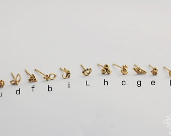 Puede incluir: Diez anillos de nariz de oro con diferentes diseños, incluyendo una flor, una hoja, un triángulo, una luna creciente, un ojo, un grupo de tres bolas, una flor, un diamante, una bola única y una flor. Los anillos están etiquetados con letras de la J a la K.