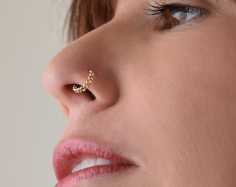 May include: A gold chain nose ring. The ring is made of a thin chain and is worn in the left nostril.