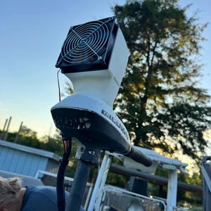 May include: A white trolling motor head unit featuring a black cooling fan mounted on top with a circular metal wire grill. The motor housing displays the brand name Minn Kota in black lettering on the side, connected to a vertical shaft.