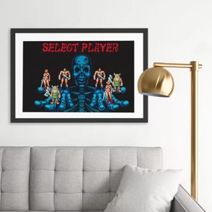 May include: Framed art print featuring a pixelated image with a black background. The image displays a blue skeleton holding pixelated characters with weapons. The text "SELECT PLAYER" is in red at the top.
