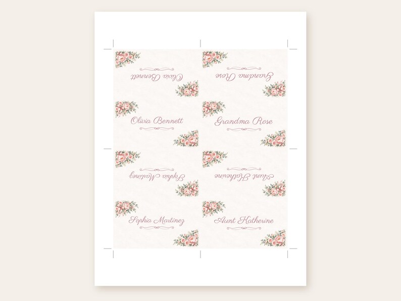May include: A sheet of eight rectangular place cards featuring a cream background with pink floral corner accents. Each card displays names in a cursive script, including Olivia Bennett, Grandma Rose, Sophia Martinez, and Aunt Katherine.