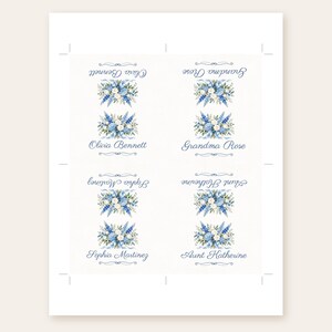 Puede incluir: Una hoja con cuatro tarjetas de sitio rectangulares que presentan un arreglo floral en acuarela de flores azules y blancas con hojas verdes. Cada tarjeta muestra un nombre en letra cursiva azul: Olivia Bennett, Grandma Rose, Sophia Martinez y Aunt Katherine.