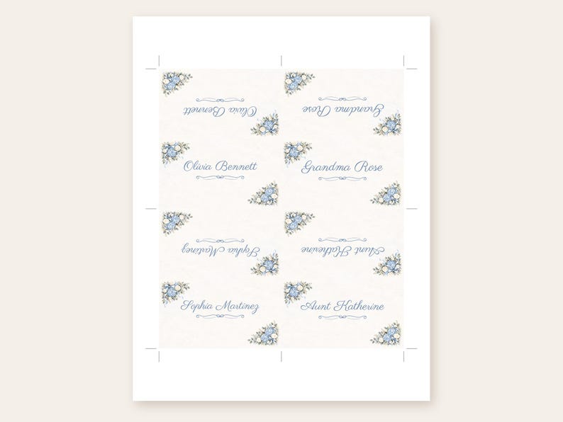 Puede incluir: Una hoja imprimible de ocho tarjetas de lugar rectangulares con fondo crema y detalles florales azules en las esquinas. Cada tarjeta muestra un nombre en letra cursiva azul, incluyendo Olivia Bennett, Grandma Rose, Sophia Martinez y Aunt Katherine.