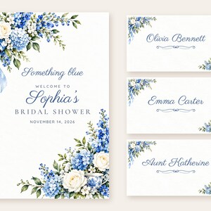 May include: A bridal shower welcome sign and three place cards featuring watercolor blue hydrangeas, white roses, and green leaves. The sign reads: Something blue, WELCOME TO Sophia's BRIDAL SHOWER, NOVEMBER 14, 2026. Place cards show names.