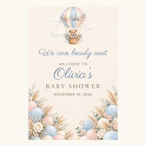 Puede incluir: Una tarjeta de invitaci&oacute;n para baby shower con un globo aerost&aacute;tico de acuarela y un osito de peluche, decorada con globos azules y rosas, hierba de la pampa y flores. El texto dice: We can bearly wait, WELCOME TO Olivia's BABY SHOWER, NOVEMBER 14, 2026.