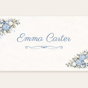 Puede incluir: Una tarjeta rectangular blanca con el nombre Emma Carter en letra azul. Las esquinas superior izquierda e inferior derecha est&aacute;n decoradas con hortensias azules, rosas blancas, hojas verdes y cintas celestes con un adorno azul debajo.