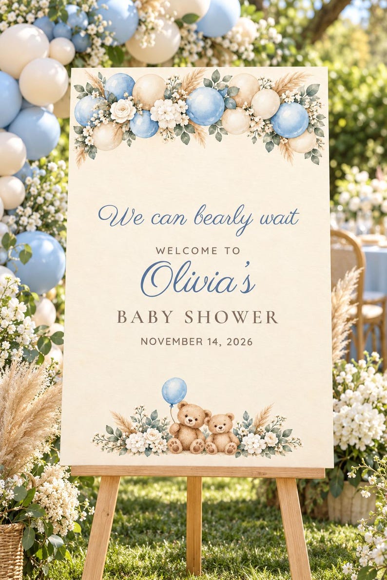 May include: A rectangular welcome sign for a baby shower featuring the text We can bearly wait, WELCOME TO Olivia's BABY SHOWER, and NOVEMBER 14, 2026. The design includes blue and cream balloons, white flowers, and two brown teddy bears.