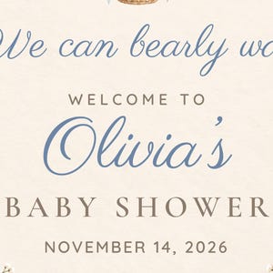 Puede incluir: Un letrero de color crema con el texto en letra cursiva azul We can bearly wait, seguido del texto WELCOME TO Olivia's BABY SHOWER y la fecha NOVEMBER 14, 2026 en letras marrones, con detalles de flores secas en las esquinas inferiores.