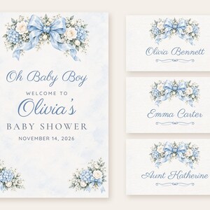 May include: A baby shower invitation and three place cards featuring watercolor blue bows, white roses, and blue hydrangeas. The text reads Oh Baby Boy WELCOME TO Olivia's BABY SHOWER NOVEMBER 14, 2026, with names Olivia Bennett, Emma Carter, and Aunt Katherine.
