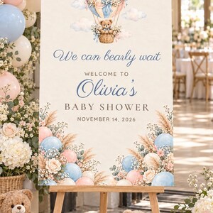 Puede incluir: Un letrero de bienvenida rectangular para un baby shower con una ilustraci&oacute;n en acuarela de un oso de peluche en un globo aerost&aacute;tico. El texto dice We can bearly wait, Welcome to Olivia's Baby Shower y November 14, 2026, con flores.
