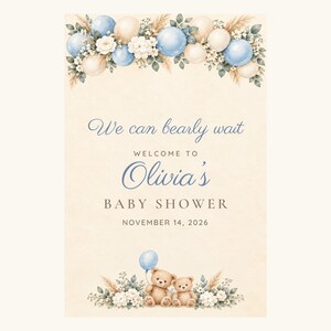 May include: A vertical sign featuring a cream background with blue and beige balloons, white flowers, and pampas grass. Text reads: We can bearly wait, WELCOME TO Olivia's BABY SHOWER, NOVEMBER 14, 2026. Two brown teddy bears sit at the bottom.