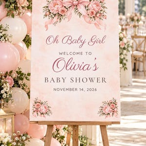K&ouml;nnte beinhalten: Ein rechteckiges Willkommensschild f&uuml;r eine Babyparty auf einer Holzstaffelei mit zartrosa Aquarellhintergrund, Blumenstr&auml;u&szlig;en und einer gro&szlig;en rosa Schleife. Der Text lautet: Oh Baby Girl WELCOME TO Olivia's BABY SHOWER NOVEMBER 14, 2026.