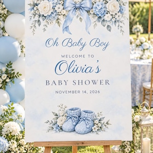 May include: A rectangular welcome sign for a baby shower featuring a light blue watercolor background, a central blue ribbon bow, white and blue floral accents, and a pair of blue knit baby booties with the text Oh Baby Boy Olivia's BABY SHOWER NOVEMBER 14, 2026.
