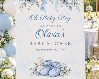 May include: A rectangular welcome sign for a baby shower featuring a light blue watercolor background, a central blue ribbon bow, white and blue floral accents, and a pair of blue knit baby booties with the text Oh Baby Boy Olivia's BABY SHOWER NOVEMBER 14, 2026.