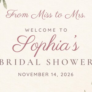 Op de afbeelding: Een cr&egrave;mekleurig bord met de tekst From Miss to Mrs. WELCOME TO Sophia's BRIDAL SHOWER NOVEMBER 14, 2026 in donkerroze en bruine letters, versierd met aquarel bloemenaccenten in de linkerbovenhoek en de rechterbenedenhoek.