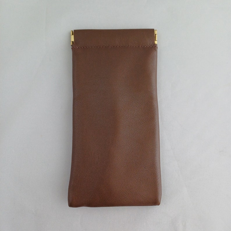 May include: A brown leather glasses case with gold metal clasps.