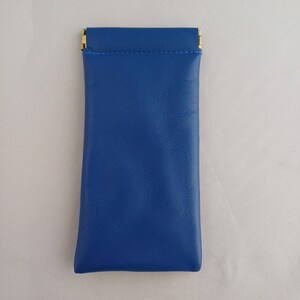 May include: A blue leather case with gold metal clasps. The case is designed to hold small items like glasses or jewelry.