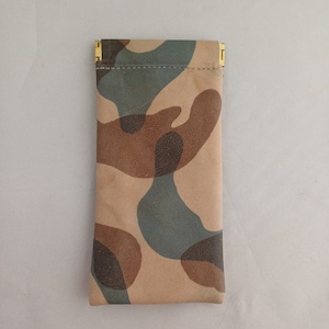 May include: A camouflage-patterned pouch with a gold zipper closure. The pouch is made of a soft, textured material.