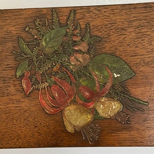 Könnte beinhalten: Eine Holzkiste mit einem floralen Design, das auf die Vorderseite gemalt ist. Die Blumen sind rot, gelb und grün.