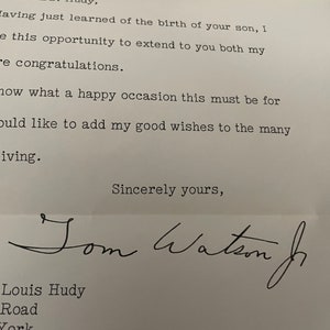 Könnte beinhalten: Eine handschriftliche Notiz auf weißem Papier mit schwarzer Tinte. Die Notiz lautet: "und Frau Hudy, Nachdem ich gerade von der Geburt Ihres Sohnes erfahren habe, möchte ich Ihnen beiden meine herzlichen Glückwünsche aussprechen.  Wissen Sie, dass dies ein glücklicher Anlass für Sie ist. Ich möchte Ihnen meine besten Wünsche zu den vielen hinzufügen, die Sie erhalten. Mit freundlichen Grüßen, Tom Watson Jr. Louis Hudy Road York"