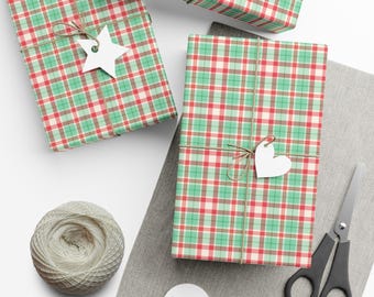 May include: Three rectangular gifts wrapped in red, green, and white plaid paper, tied with twine. One gift features a white star-shaped tag, another a white heart-shaped tag. A ball of white twine, scissors, and blank white tags are included.