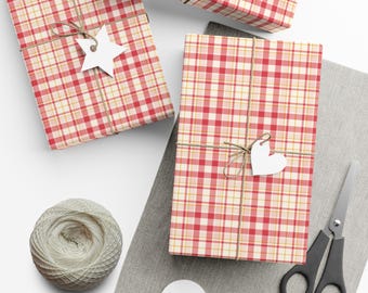 May include: Three rectangular packages wrapped in red, pink, and yellow plaid paper, tied with brown twine. One package features a white star-shaped tag, another a white heart-shaped tag, accompanied by a ball of twine and scissors.