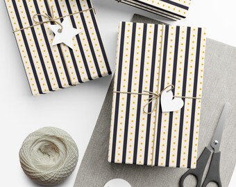 May include: Three rectangular gift boxes wrapped in cream paper with vertical navy blue stripes and small gold stars. Each box is tied with brown twine and features a white paper gift tag in the shape of a star or heart.