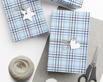 May include: Two rectangular gifts wrapped in light blue, white, navy, and red plaid paper, tied with brown twine. One gift features a white star-shaped tag, the other a white heart-shaped tag. A ball of twine and scissors are nearby.