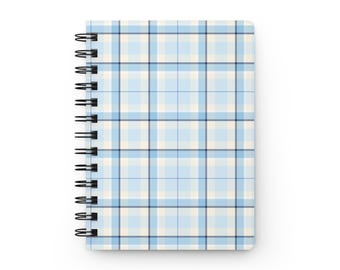 May include: A spiral-bound notebook featuring a light blue, white, and dark blue plaid pattern. The cover has a grid of intersecting horizontal and vertical lines in varying shades of blue and white, secured by a black metal wire coil.