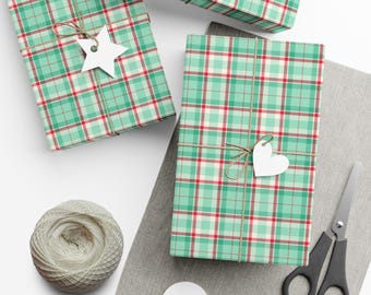 May include: Three rectangular packages wrapped in mint green, white, and red plaid paper. Each package is tied with thin brown twine and features a white paper gift tag in the shape of a star or heart. A ball of white yarn and black scissors.