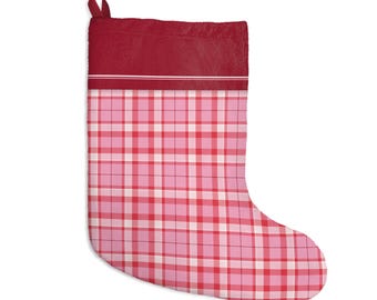 May include: A Christmas stocking featuring a solid dark red cuff with a thin white horizontal line accent. The main body of the stocking displays a pink, light pink, and white plaid pattern with thin dark red grid lines throughout.