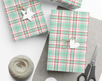 May include: Two rectangular packages wrapped in mint green, white, and red plaid paper, tied with twine. One package features a white star-shaped gift tag, while the other has a white heart-shaped tag. A ball of twine and black scissors are included.