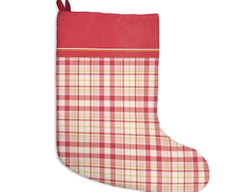 May include: A Christmas stocking featuring a solid red cuff at the top with a thin white and yellow horizontal stripe below it. The main body of the stocking displays a red, white, and yellow plaid pattern. A small red fabric loop is attached.