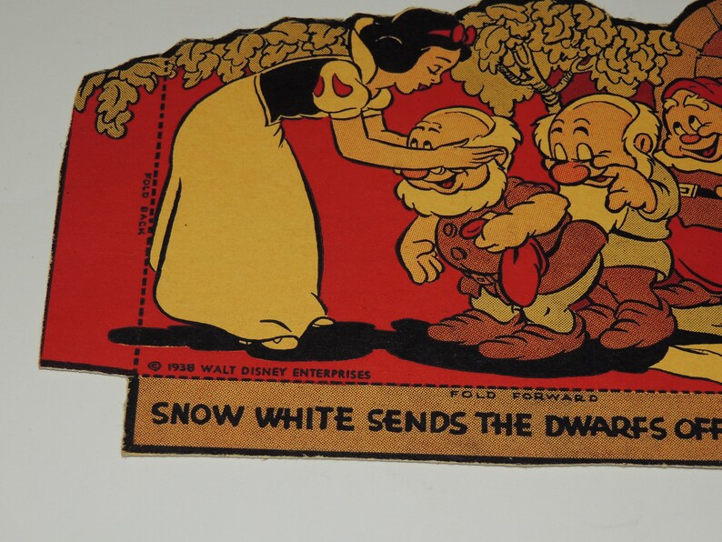 May include: A vintage paper doll set featuring Snow White and the Seven Dwarfs. Snow White is dressed in a yellow dress and black bodice, and she is bowing to the dwarfs. The dwarfs are wearing brown pants and red shirts. The paper doll set is printed on a red background with a yellow border. The text "Snow White Sends the Dwarfs Off" is printed on the bottom of the paper doll set.