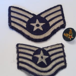 May include: Two dark blue embroidered military rank patches featuring three white chevrons and a central white star, accompanied by a small circular lapel pin with a gold wing emblem, a central red dot, and a gold star on a dark blue background.