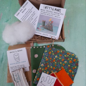Puede incluir: Un kit de costura para hacer dos juguetes de pollo de fieltro. El kit incluye recortes de tela, fieltro, botones, hilo y un patr&oacute;n. El kit est&aacute; empaquetado en una caja de cart&oacute;n marr&oacute;n con una etiqueta blanca que dice "Betty & Mabel Mabel Chicken Sewing Kit Thoughtfully created from recycled materials. (Makes 2)"