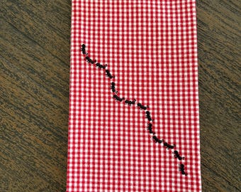 A Red And White Checked Tea Towel With Ant Embroidery