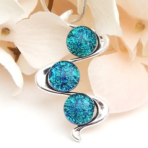 Peut inclure: Collier avec pendentif en argent avec trois cercles en verre bleu turquoise. Les cercles ont une finition texturée et scintillante.