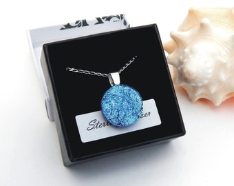 Peut inclure: Un collier avec un pendentif en verre bleu et une chaîne en argent dans une boîte noire. Le pendentif est rond et a une texture scintillante. La boîte a une étiquette blanche qui dit "Sterling Silver".