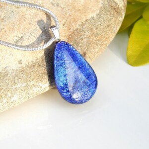 Puede incluir: Un collar con un colgante en forma de l&aacute;grima con una cadena de plata. El colgante est&aacute; hecho de vidrio azul con un acabado brillante.