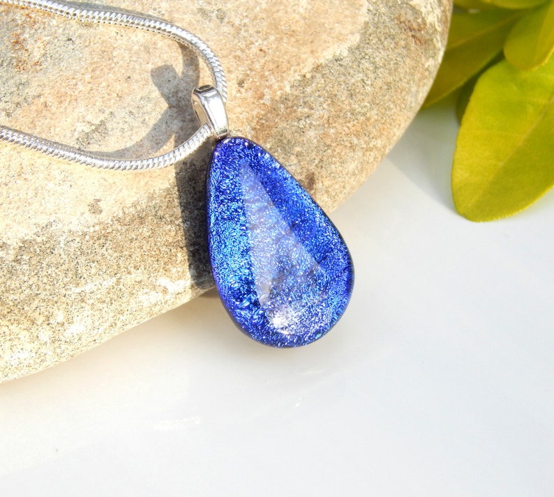 Puede incluir: Un collar con un colgante en forma de l&aacute;grima con una cadena de plata. El colgante est&aacute; hecho de vidrio azul con un acabado brillante.