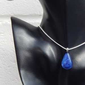 Puede incluir: Un collar de cadena de plata con un colgante en forma de l&aacute;grima de vidrio dicroico azul.